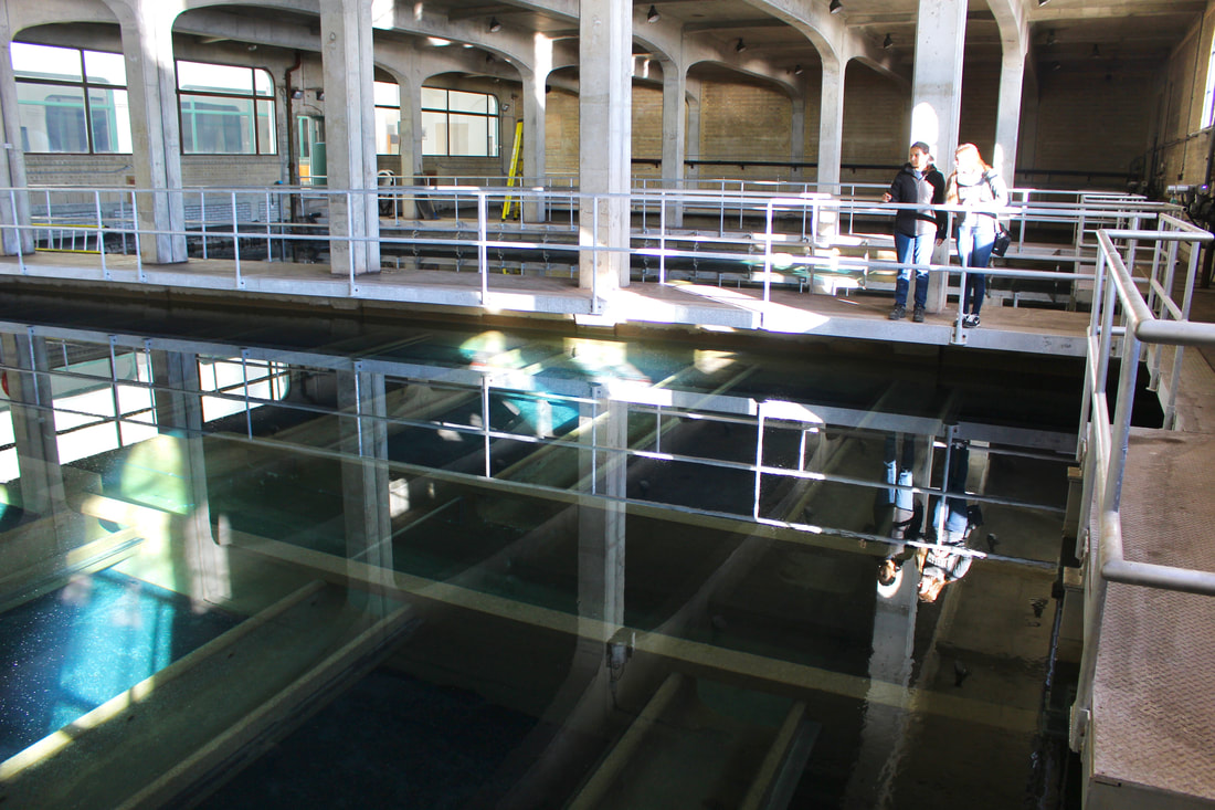 Two women in a drinking water plant looking at large settling pools
