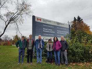 6 researchers stand in front of the Natural Resources Canada Great Lakes Forestry Centre  sign