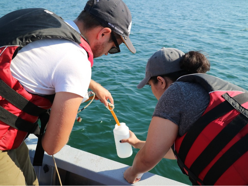 Two students taking water samples from the boat